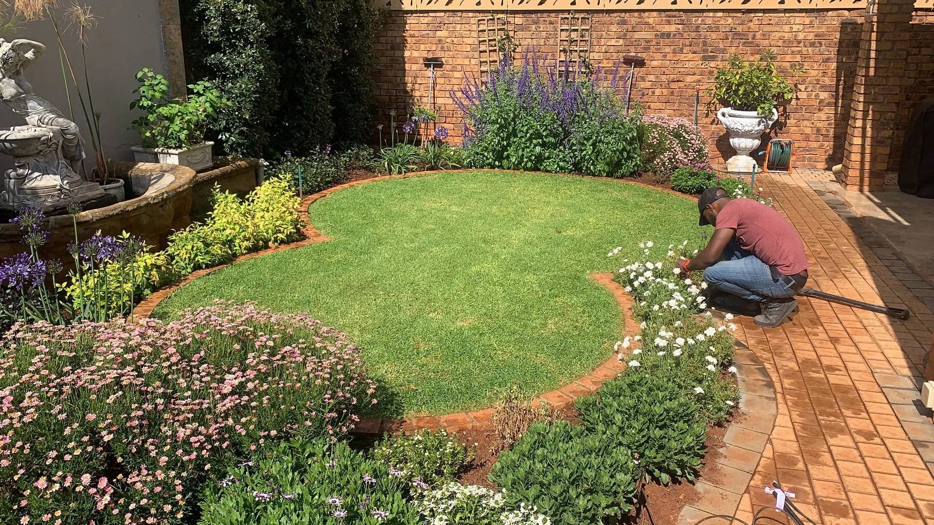 Turfex-built garden in full bloom in Pretoria East, with a Turfex gardener tending the beds