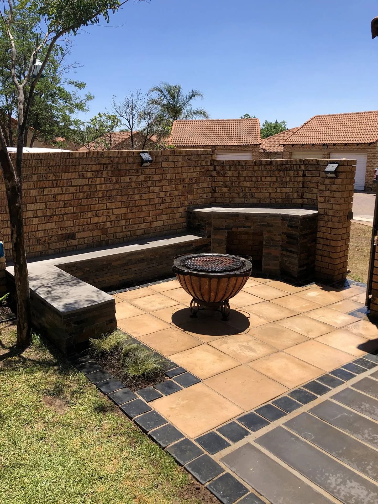 Sunlit firepit courtyard with built-in benches, built by Turfex